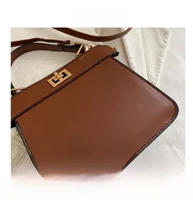 Nahaufnahme der braunen Kunstledertasche mit goldenem Drehverschluss und schwarzen Nähten