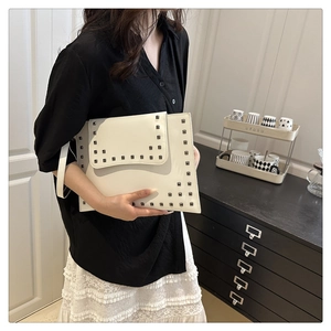 Detail view of cream leather envelope clutch with stylish square metal rivets on side