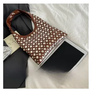 Brown leather rivet hobo bag next to iPad showing spacious interior and large capacity