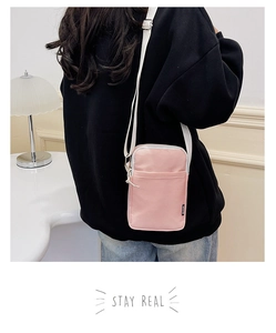Detail of pink nylon crossbody bag worn by model in a cozy indoor lifestyle setting