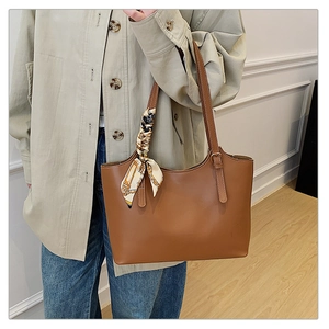 Brown leather tote bag with silk scarf detail shown on shoulder for office look