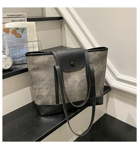 Détail du sac cabas en toile grise avec bordures en cuir noir et fermeture à pression