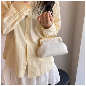 Detail of elegant cream-colored jacquard bag with traditional pattern and gold metal clasp