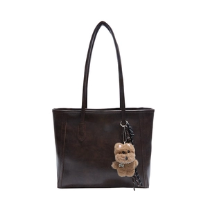 Deep brown vintage leather tote bag with simple trapezoid structure and cute bear charm