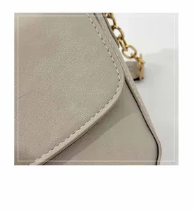 Macro detail of beige shoulder bag with fine stitching and gold metal chain strap