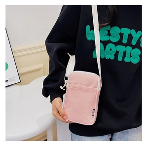 Close-up of pink corduroy crossbody phone bag with adjustable strap and sport tag