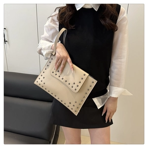Detailed close-up of light beige envelope clutch bag with square metal rivet embellishments