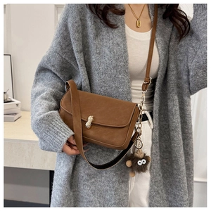 Brown retro crossbody bag with golden peanut buckle and plush charm detail on strap