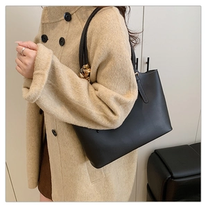 Detail of minimalist black faux leather tote bag with silk scarf on a shoulder strap