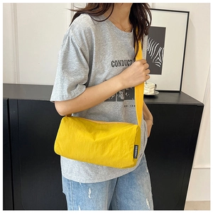 Close-up of bright yellow nylon crossbody bag featuring minimalist logo detail