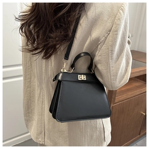 Detail der klassischen schwarzen Ledertasche mit goldenem Drehverschluss und Faltung