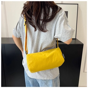 Detailed view of yellow cylindrical nylon crossbody bag with adjustable strap and side label