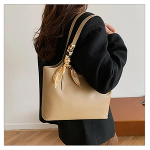 Fashionable khaki tote bag with a vintage silk scarf handle accessory shown with model