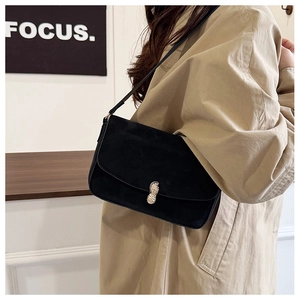 Close-up of black suede shoulder bag featuring a unique gold peanut-shaped metal buckle