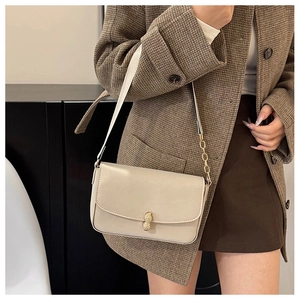 Detail of cream flap bag with gold peanut buckle and chain strap on a blazer outfit