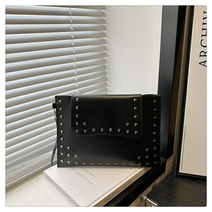 Macro shot of silver square rivets on high-quality black leather envelope clutch bag