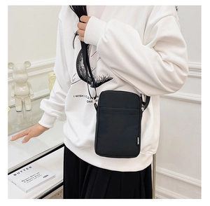 Close-up of black nylon crossbody phone bag with SPORT label worn on the waist side
