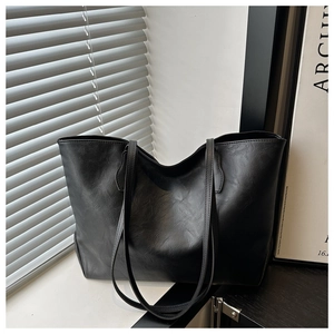 Detail of minimalist black tote bag with natural leather texture and sleek straps