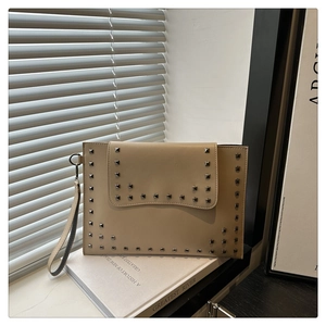 Close-up of oatmeal envelope clutch bag with silver square studs and leather wrist strap