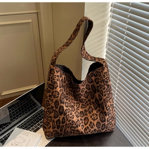 Détail d'un grand sac cabas à imprimé léopard posé sur un bureau sous une lumière chaude