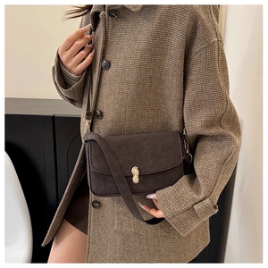 Close-up of a dark brown retro shoulder bag featuring a unique gold peanut-shaped buckle