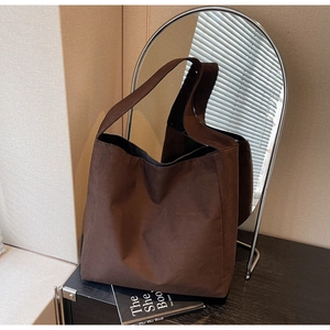 Détail du grand sac cabas en daim marron foncé sur étagère au style minimaliste
