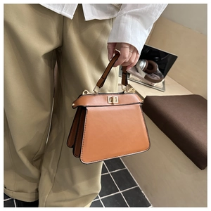 Detailaufnahme der braunen Ledertasche mit goldenem Drehverschluss und klassischem Handgriff