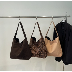 Détails de grands sacs fourre-tout en marron foncé, imprimé léopard et beige sur cintres