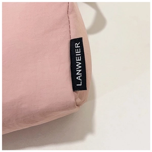 Detail of pink nylon fabric texture with black brand logo tag and premium stitching