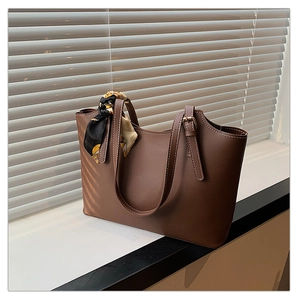 Detailed view of brown leather tote bag with silk scarf accent and elegant stitching