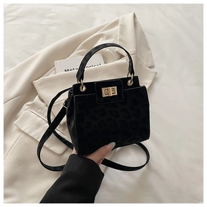 Détail du sac en daim léopard noir avec fermoir doré rotatif et bandoulière élégante