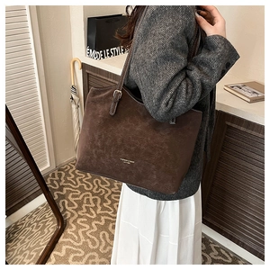 Detail view of deep brown suede tote bag with golden fashion text in life scene