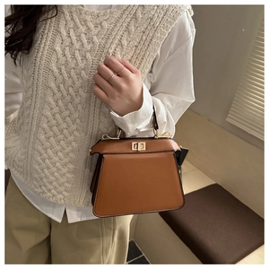 Nahaufnahme braune Lederhandtasche mit goldenem Drehverschluss und eleganter Trapezform