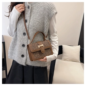 Close-up of vintage brown crossbody bag with letter monogram print and gold buckle