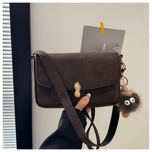 Detail of vintage brown matte leather bag with golden peanut clasp and plush charm