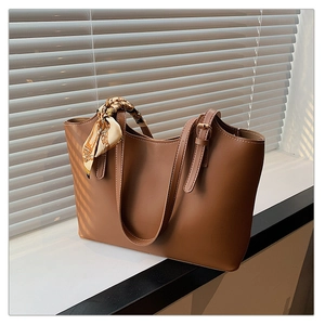 Brown faux leather tote bag with elegant silk scarf wrapped on the handle with shadows