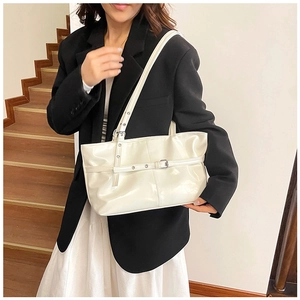 Détail du sac à bandoulière en cuir verni blanc avec boucle et œillets métalliques sur l'anse