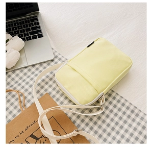 Detail of light yellow nylon crossbody bag with adjustable strap on checkered tablecloth