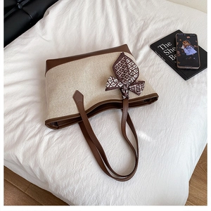 Dettaglio borsa tote in tela beige con finiture in pelle marrone e foulard in seta