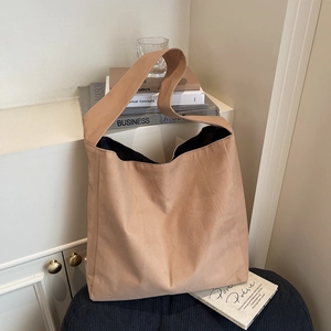Grand sac cabas kaki minimaliste avec large bandoulière posé sur un fauteuil doux