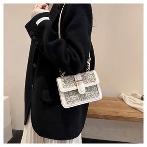 Close-up of cream crossbody bag featuring letter monogram and gold-tone metal lock