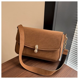 Detail of a brown suede shoulder bag featuring a unique golden peanut-shaped metal buckle