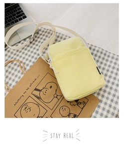 Detail of light yellow nylon phone bag with adjustable strap and smooth zipper closure