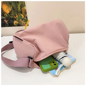 Pink nylon cylinder crossbody bag showing large capacity with umbrella and phone inside