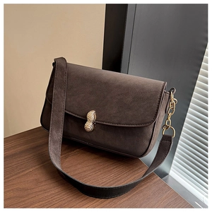 Detail of dark brown suede shoulder bag featuring a gold peanut shaped metal buckle