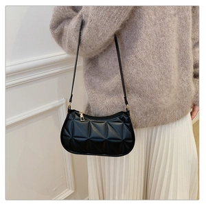 Détail du sac d'épaule noir matelassé avec fermeture éclair dorée et similicuir texturé