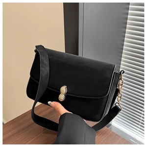Detail of elegant black shoulder bag featuring unique gold peanut-shaped metal clasp