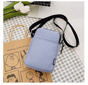 Detail view of a lavender nylon crossbody phone bag with an adjustable strap and SPORT label