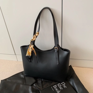 Minimalist black leather tote bag with printed silk scarf accent and long shoulder straps