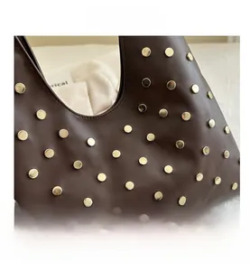 Gros plan détaillé du sac en cuir marron mat avec des ornements en rivets dorés ronds